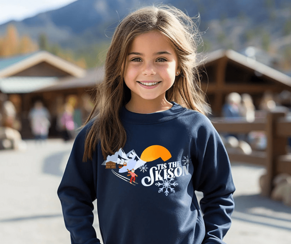 Girl wearing navy jumper with 'Tis the Skison' graphic on it