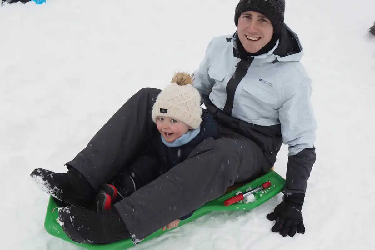 Family skiing in Valmorel: Enjoying sledging down the slopes