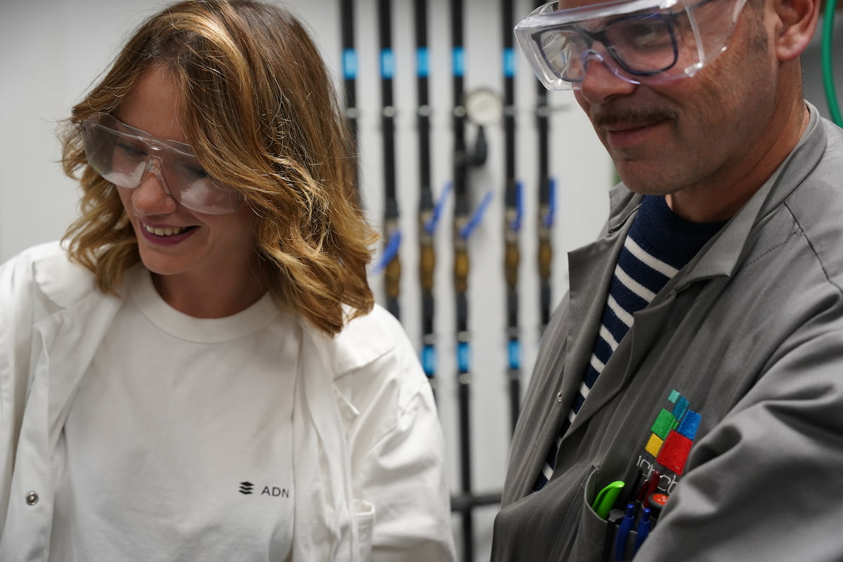 Camille Lambert wearing scientific goggles, working with a member of her team